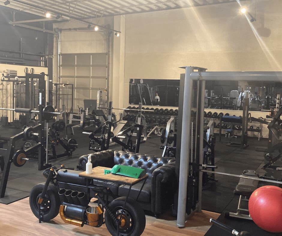 Freihantelbereich im Studio Germersheim mit Hantelablage, Chesterfield-Sofa und einem Motorrad als Dekoration